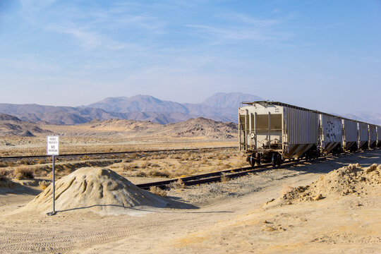A train in trona pinnacles going through the Mojave desert, eventually intersecting with this empty dirt road.