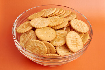 A bowl of round crackers on a yellow background. A tasty and sweet snack.