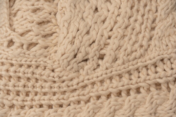 A fragment of beige knitted fabric, knitted from white sheep wool.