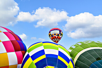 Colorful hot air balloon flying over blue sky with white clouds	