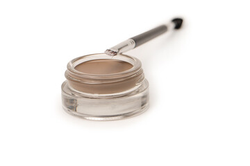 A brow pomade in blonde shade with brush isolated on a white background.