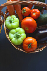 Two wicker baskets with healthy seasonal fruit and vegetable. Dark background, top view.