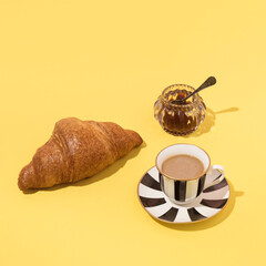 Fresh croissant, a cup of coffee latte , fruity jam, creative morning coffee and breakfast layout. 