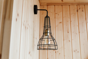 Interior detail. Stylish scandinavian composition of black bra with vintage edison lamp and wooden...
