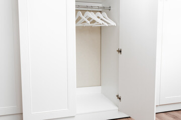 White empty wardrobe closet with hangers. Wooden white hangers on a rod. Store, sale, advertisement concept.