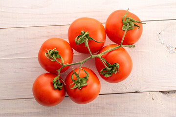 Several fresh tomatoes on branch  on wooden table, macro, top view.