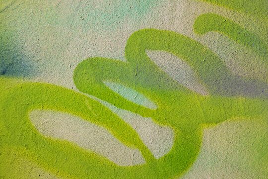 Fototapeta Fragment of old plaster wall with graffiti painting. Part of colorful street art graffiti on wall background. Youth, urban culture. Yellow, green colors