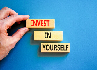 Invest in yourself symbol. Concept words Invest in yourself on wooden block on a beautiful blue table blue background. Businessman hand. Business and Invest in yourself concept. Copy space.