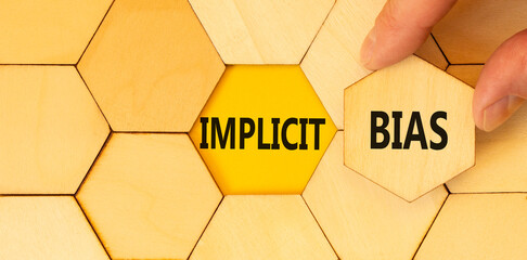 Implicit bias symbol. Concept words Implicit bias on wooden puzzles. Beautiful yellow table yellow background. Businessman hand. Business psychology implicit bias concept. Copy space.