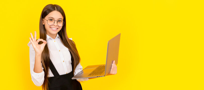 happy child in school uniform and glasses study on laptop with ok gesture, e learning. School girl portrait with laptop, horizontal poster. Banner header with copy space.