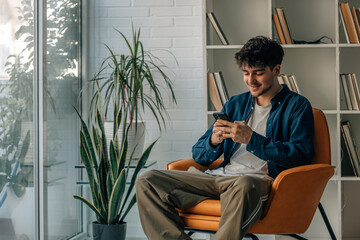young man at home looking at mobile phone on the sofa