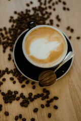A cup of latte coffee on the table stands in coffee beans close-up