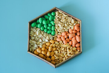 Six varieties of multi-colored roasted glazed peanuts in a hexagonal craft box on a white...