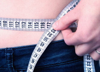 Woman measuring her waistline. Concept of diet and healthy lifestyle.