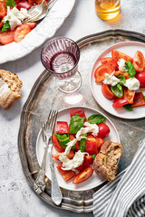 Tomatoes, bell pepper, mozzarella and basil Salad. Bread, olive oil, cutlery. Healthy mediterranean food.  Caprese. Appetizing laid table. Top view.