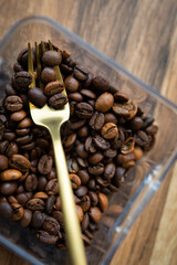 Roasted coffee bean in a plastic box along with a fork, close-up, top view. The concept of making coffee.