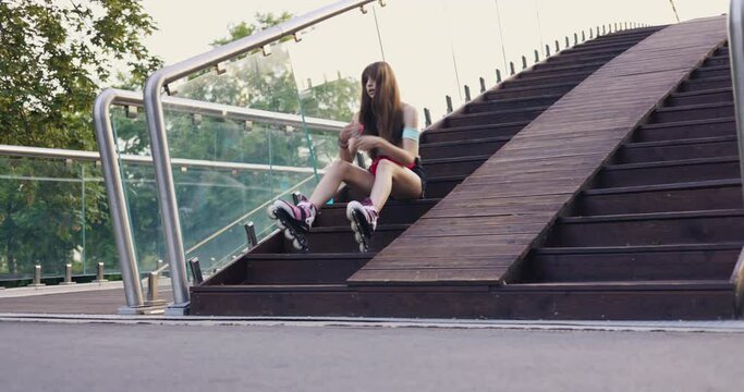 Tired skater girl rests sitting on stairs