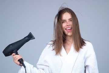 Woman with hair dryer on studio background. Girl hold hairdryer. Young woman drying hairs with hair...