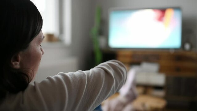 Woman watching television at home and eating chips