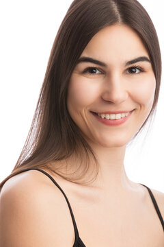 Portrait of a beautiful caucasian woman in her 20s. The background is white and she is wearing a black tank top. She is smiling in her headshot. She has brown hair and brown eyes.