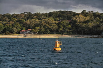 Fototapeta na wymiar Red lateral mark buoy off Shark Bay beach afoot Nielsen Park-Federation style kiosk on the waterfront. Sydney-Australia-555