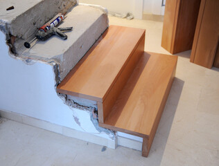Trabajos de carpintería e interiorismo. Preparación de los escalones de hormigón de la escalera de una casa para pegar sobre ellos los peldaños de madera de haya con silicona de alta resistencia  © joserpizarro