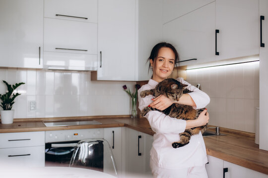 Young Woman Playing With Cat In Kitchen At Home.