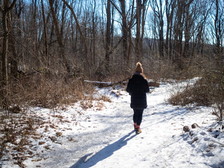 young woman hiking on frozen path on a cold sunny winter day
