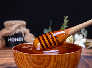Honey spoon coming out of the bowl full of honey. Honey contains many nutrients, antioxidants, improves heart health, wound care, offers antidepressant and anti-anxiety benefits.