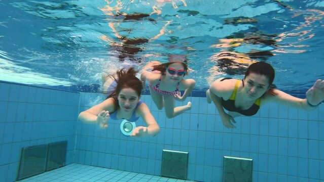 Young mother girl with preteen daughter child and teenager swimming in pool under water together. Family diving lessons