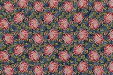 abstract background texture blue denim fabric closeup with a pattern of pink embroidered roses