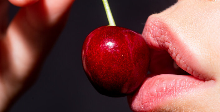 Macro cherry in woman mouth. Cherries on woman lips. Glamour art lips concept.