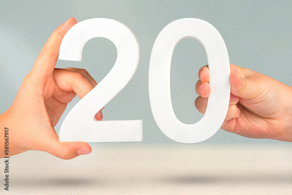 Poster number twenty in hand. hand holding white number 20 on blurred background with copy space. concept w