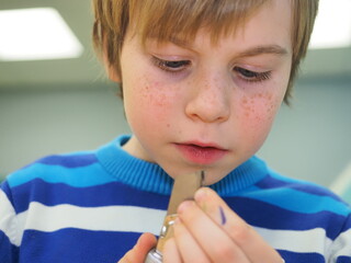 boy with red hair in a blue sweater is making a boat out of Styrofoam