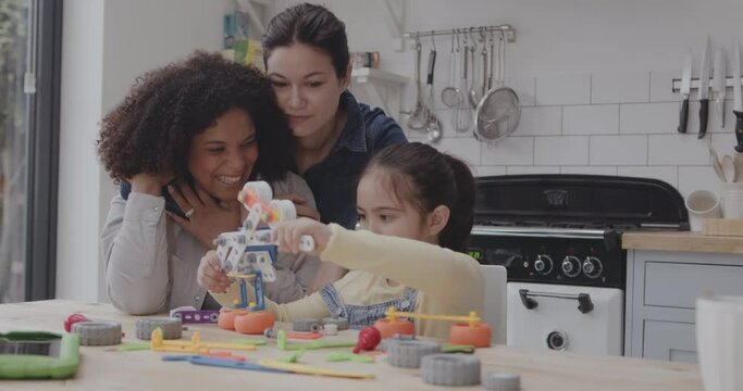 Child at the Kitchen Table Playing with Robot together with Parents