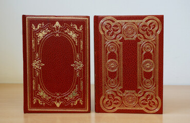 Two red cover vintage books bound in leather and decorated with gold details - obrazy, fototapety, plakaty