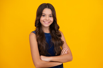 Obraz premium Happy girl face, positive and smiling emotions. Teenage girl kid with crossed arms, looking at camera, isolated on yellow studio background.
