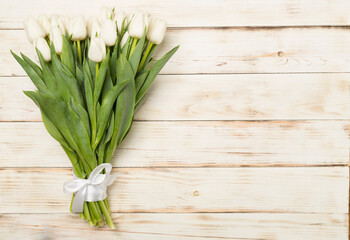 White tulip bouquet on wooden background, top view