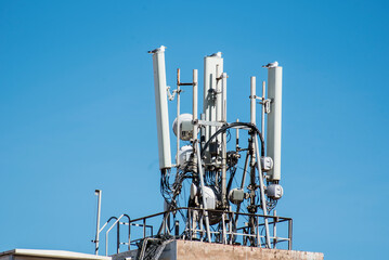 Telecommunication tower with antennas on blue sky background, closeup of photo