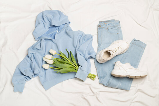 Stylish pastel spring outfit on white sheet background, top view