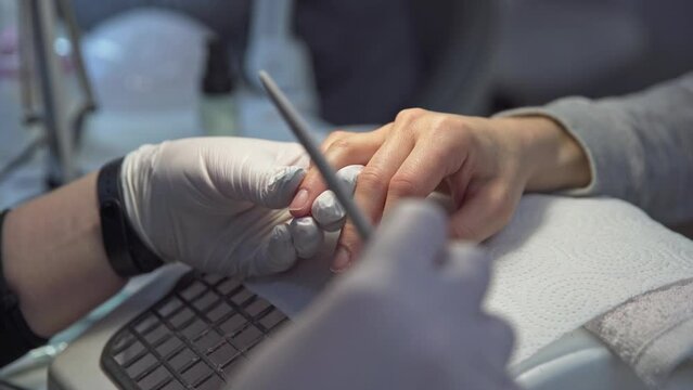 Employee saws nails of beauty salon customer