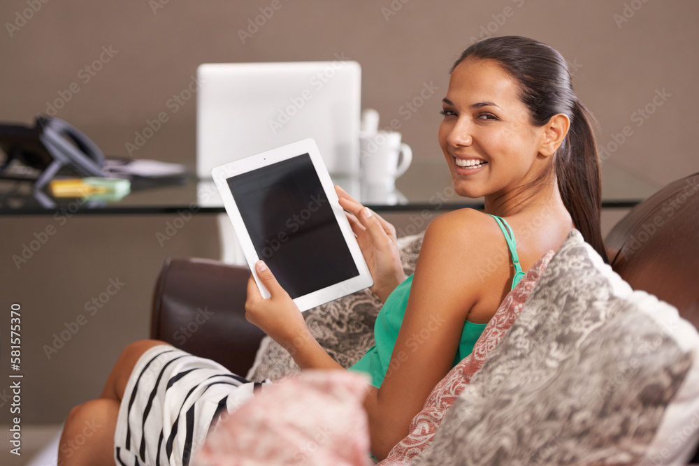 Canvas Prints Taking a break to catch up with my e-books. A smiling young woman holding a digital tablet at home.