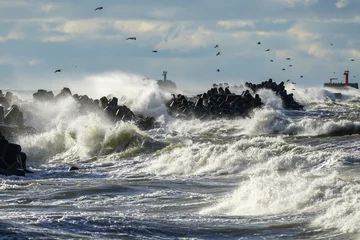 Tuinposter Coastal storm in the Baltic Sea, big waves crash against the harbor breakwater, breaking wave © Zigmunds