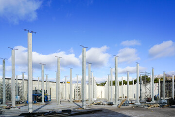 Many white vertical reinforced concrete columns at the construction site of an industrial facility