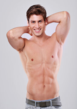 Im all man. Studio shot of a handsome bare chested young man with his hands behind his head.
