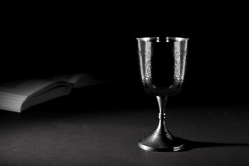 christian chalice with open bible in the background. black and white photography