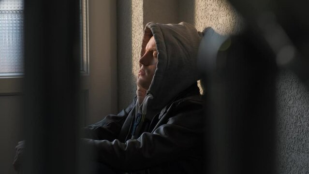 A young desperate depressed teenager in a hood sits on the landing in the entrance