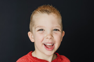 Portrait of a boy smiling with a plain black background