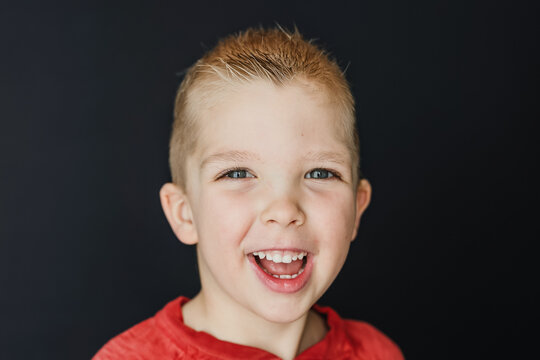 Portrait Of A Boy Smiling With A Plain Black Background