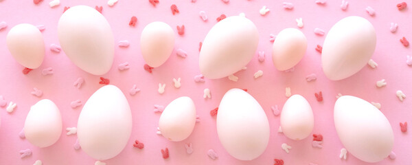 Pink Big and small Easter eggs and confetti on pink background. Egg hunting.